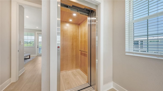 interior space featuring baseboards, elevator, recessed lighting, and wood finished floors