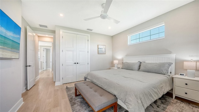 bedroom with light wood-style flooring, a closet, visible vents, baseboards, and ceiling fan