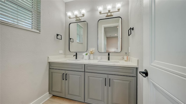 full bathroom with a sink, double vanity, and baseboards