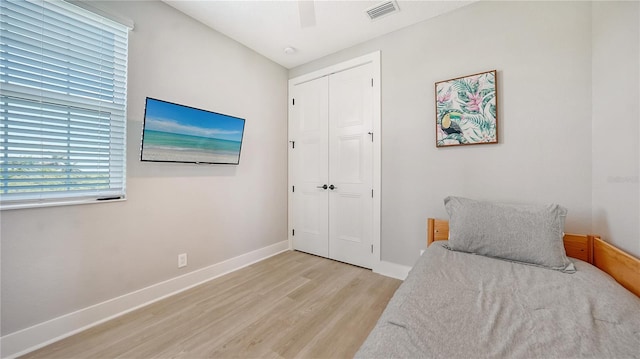 bedroom featuring a closet, visible vents, baseboards, ceiling fan, and light wood-style floors