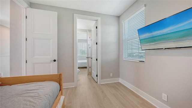 bedroom with baseboards, multiple windows, and light wood-style floors