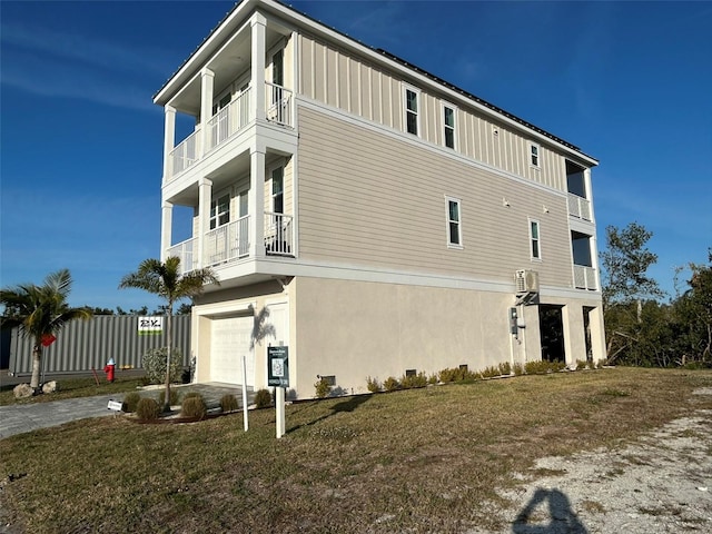 view of side of home featuring board and batten siding, an attached garage, a lawn, and a balcony