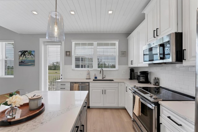 4207 Marina View Way, Cortez, FL 34215 - kitchen featuring appliances with stainless steel finishes, light wood-type flooring, white cabinets, pendant lighting, and tasteful backsplash