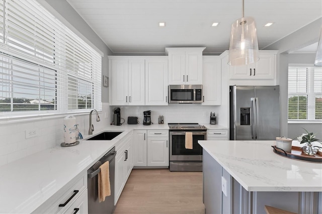 4207 Marina View Way, Cortez, FL 34215 - kitchen featuring stainless steel appliances, decorative backsplash, light wood-style floors, white cabinets, and light stone countertops