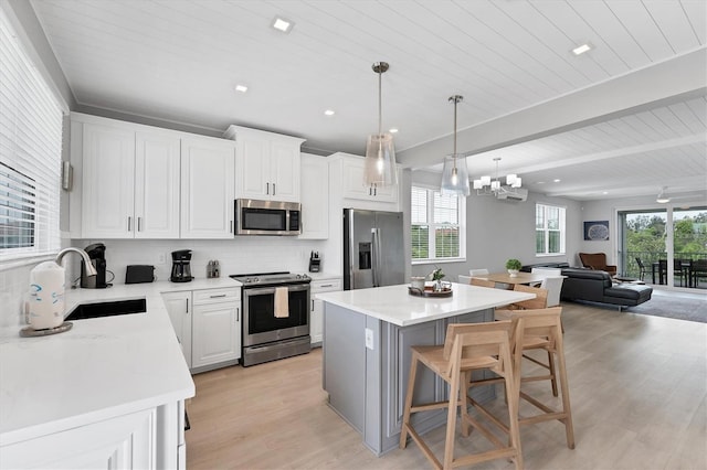 4207 Marina View Way, Cortez, FL 34215 - kitchen with stainless steel appliances, light wood-style floors, open floor plan, a center island, and tasteful backsplash