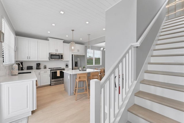 4207 Marina View Way, Cortez, FL 34215 - kitchen with stainless steel appliances, a breakfast bar, light wood-style floors, white cabinets, and light countertops