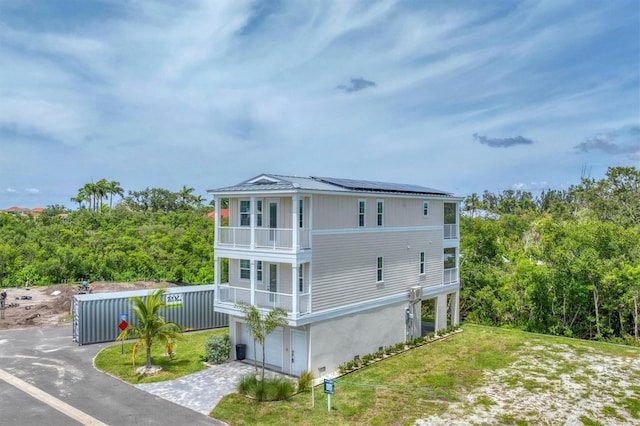 4207 Marina View Way, Cortez, FL 34215 - view of side of home featuring a balcony, solar panels, driveway, a metal roof, and a yard
