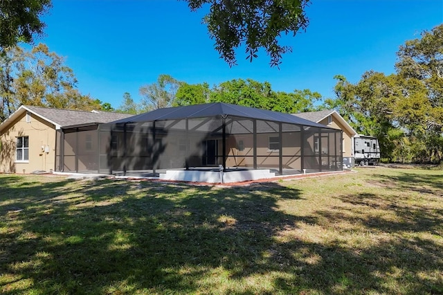 back of house featuring glass enclosure and a yard