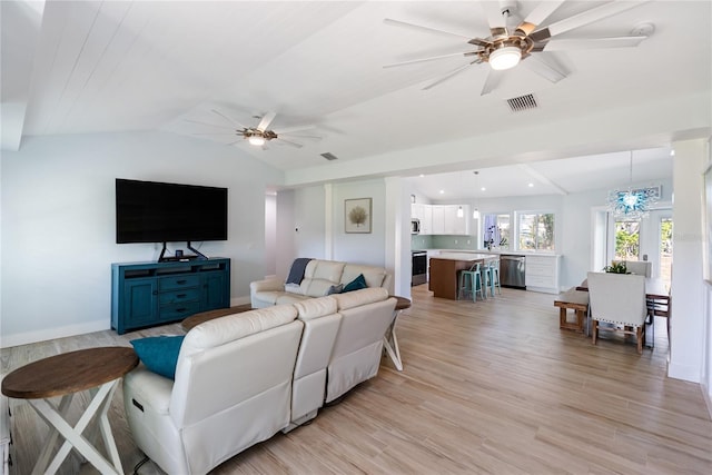 living room with ceiling fan with notable chandelier, vaulted ceiling, and light wood-type flooring