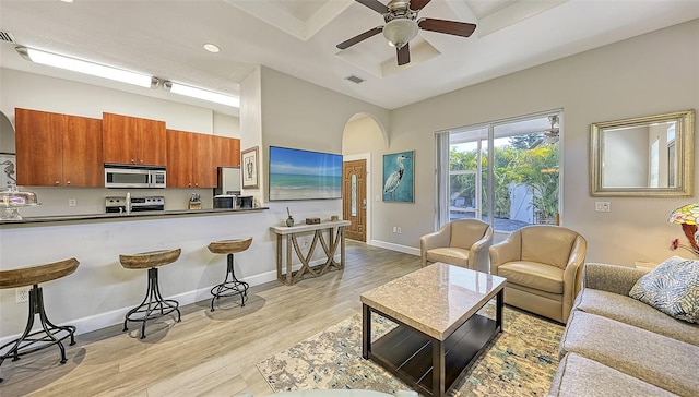 living room featuring ceiling fan, coffered ceiling, and light hardwood / wood-style floors