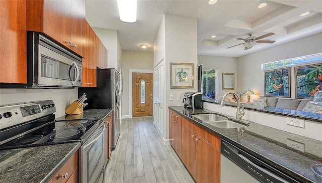 kitchen featuring stainless steel appliances, sink, dark stone countertops, and light wood-type flooring