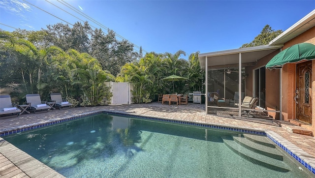 view of swimming pool with a grill, a patio area, and ceiling fan