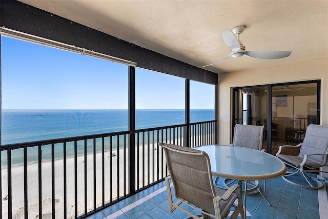 sunroom with a water view, a beach view, and ceiling fan