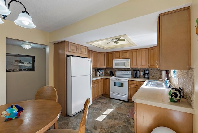 kitchen featuring sink, decorative backsplash, ceiling fan, a raised ceiling, and white appliances