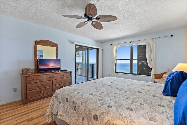 bedroom featuring ceiling fan, access to outside, a textured ceiling, and light wood-type flooring