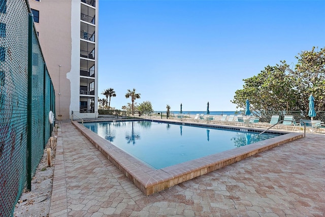 view of swimming pool with a patio and a water view