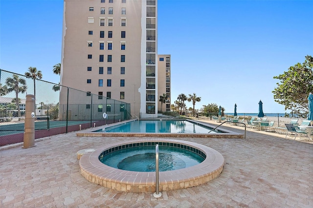 view of swimming pool with a water view, a patio area, tennis court, and a community hot tub