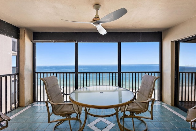 sunroom / solarium featuring tile patterned flooring and a water view
