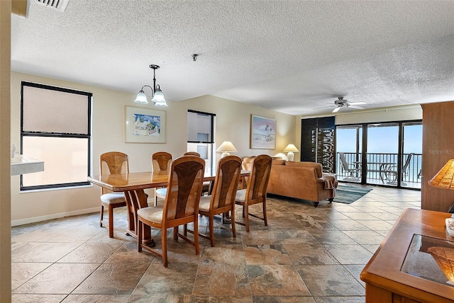 dining space with a textured ceiling, ceiling fan with notable chandelier, stone finish flooring, baseboards, and visible vents