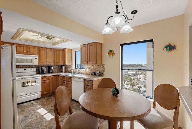kitchen with light countertops, white appliances, tasteful backsplash, hanging light fixtures, and ceiling fan