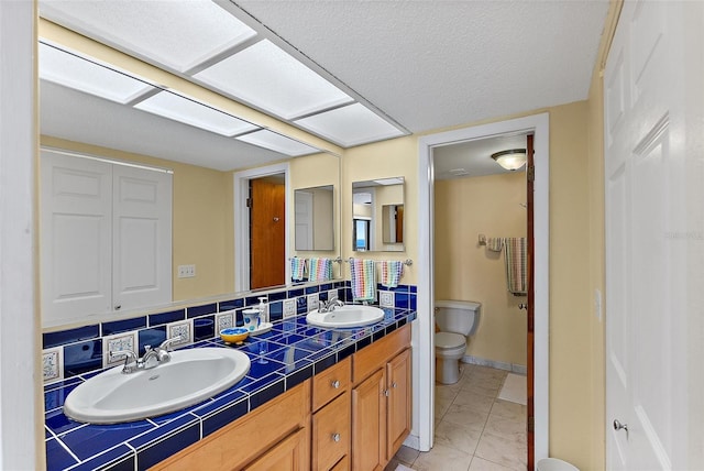 bathroom with marble finish floor, double vanity, toilet, and a sink