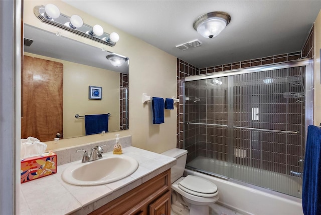 bathroom with visible vents, vanity, shower / bath combination with glass door, and toilet