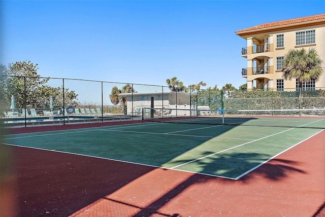 view of tennis court with community basketball court and fence