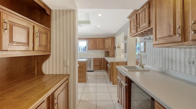 kitchen with light tile patterned floors, stainless steel dishwasher, and sink