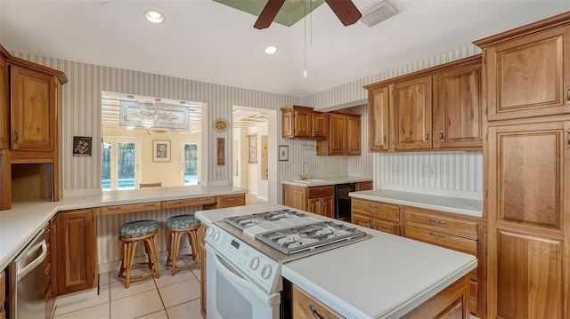 kitchen featuring light tile patterned floors, sink, dishwasher, a center island, and white gas range