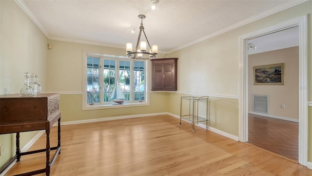 unfurnished dining area with an inviting chandelier, crown molding, and light hardwood / wood-style flooring