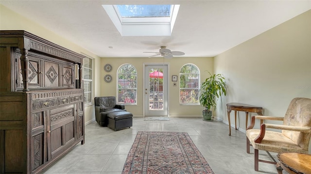 sitting room with light tile patterned floors, a skylight, and ceiling fan