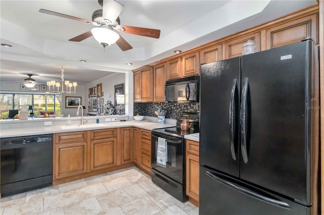 kitchen featuring sink, tasteful backsplash, an inviting chandelier, a tray ceiling, and black appliances