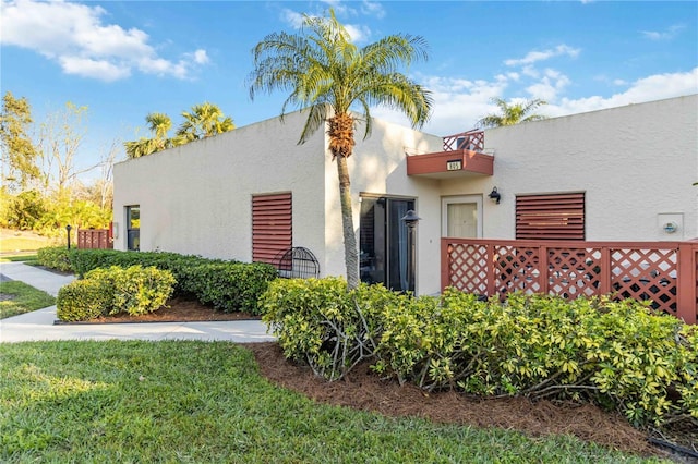 view of side of property featuring a yard and a balcony