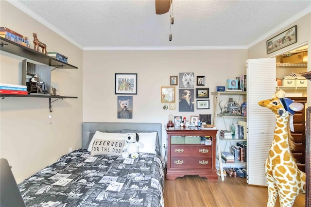 bedroom featuring ceiling fan, hardwood / wood-style flooring, ornamental molding, and a textured ceiling