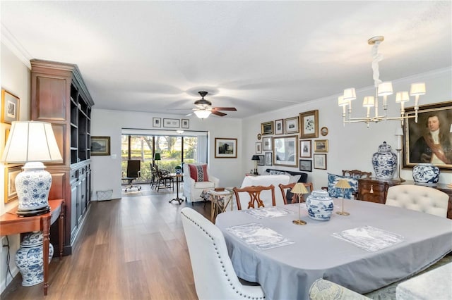 dining space featuring dark hardwood / wood-style flooring, crown molding, and ceiling fan with notable chandelier