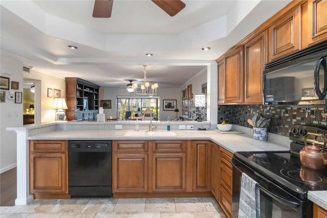 kitchen featuring sink, black appliances, a tray ceiling, ceiling fan with notable chandelier, and backsplash