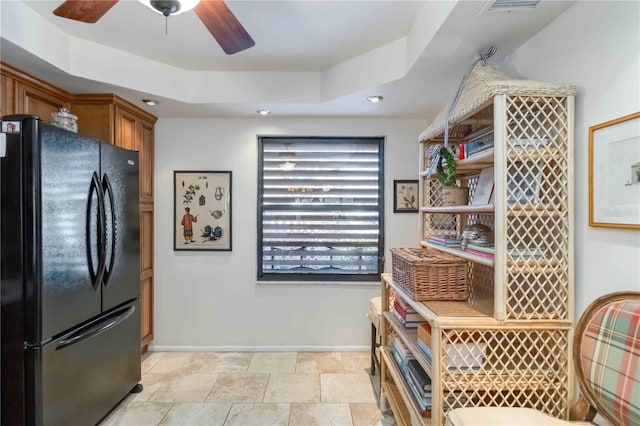 kitchen with black refrigerator, ceiling fan, and a tray ceiling