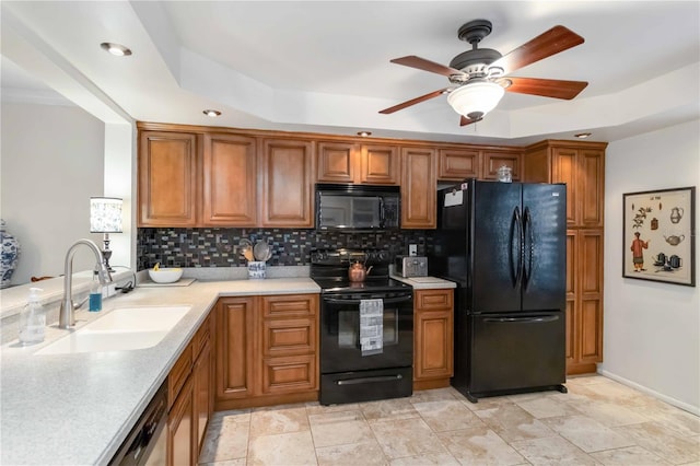 kitchen featuring black appliances, sink, decorative backsplash, ceiling fan, and a tray ceiling