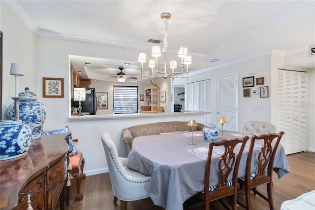 dining space with hardwood / wood-style flooring, crown molding, and ceiling fan with notable chandelier