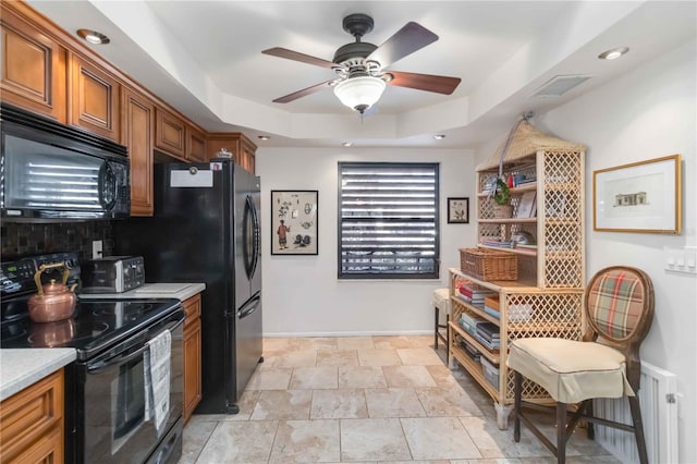 kitchen with radiator heating unit, black appliances, a raised ceiling, and ceiling fan