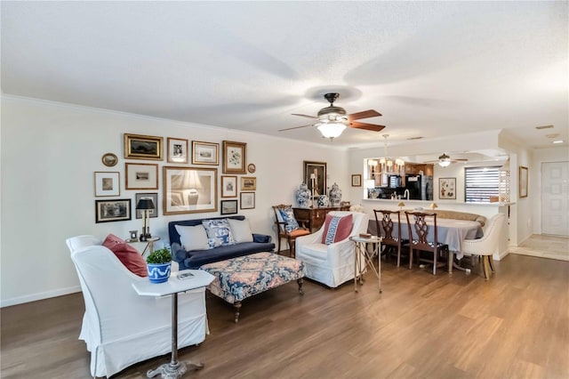 living room featuring ceiling fan with notable chandelier, ornamental molding, hardwood / wood-style floors, and a textured ceiling