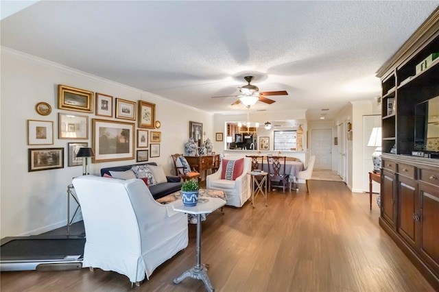 living room featuring crown molding, ceiling fan, light hardwood / wood-style floors, and a textured ceiling