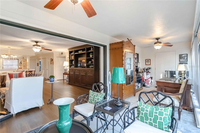 living room with ceiling fan with notable chandelier and hardwood / wood-style floors