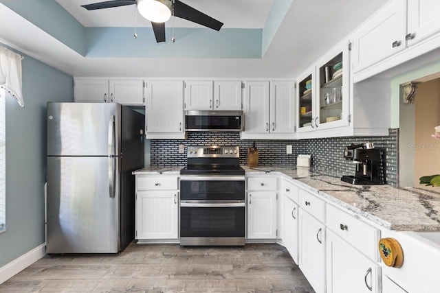 kitchen with stainless steel appliances, white cabinetry, and tasteful backsplash