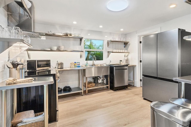 kitchen featuring sink, stainless steel fridge, light hardwood / wood-style floors, and decorative backsplash