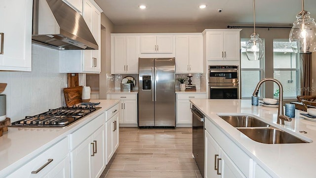 kitchen featuring ventilation hood, white cabinetry, appliances with stainless steel finishes, and sink