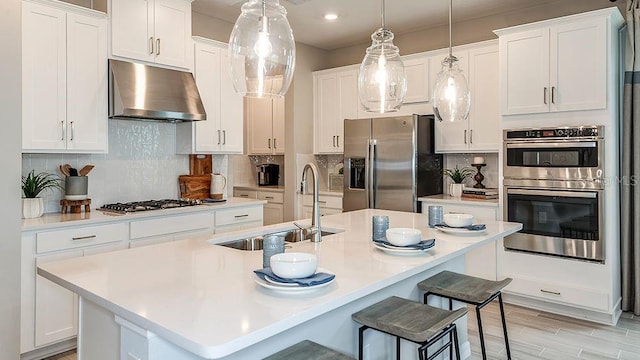 kitchen featuring a kitchen island with sink, white cabinets, and appliances with stainless steel finishes