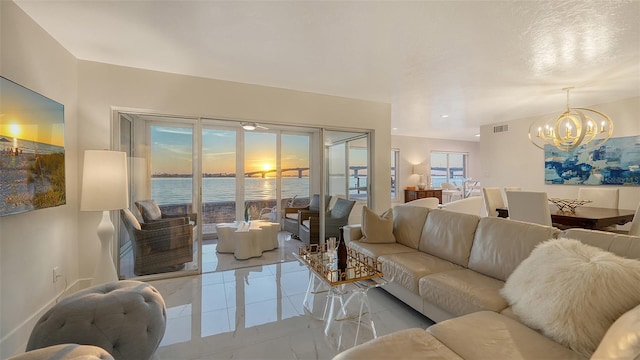 tiled living room with a water view and a chandelier