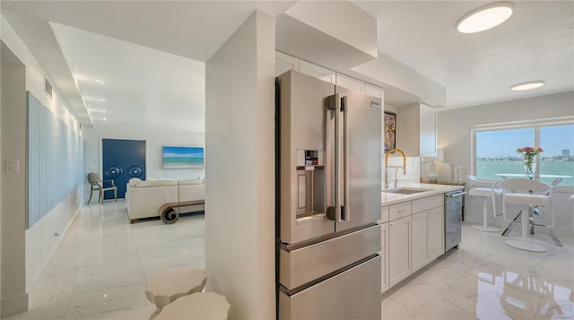 kitchen featuring white cabinetry, sink, stainless steel appliances, and a water view