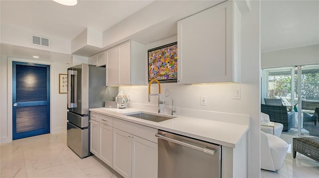 kitchen with stainless steel appliances, sink, and white cabinets